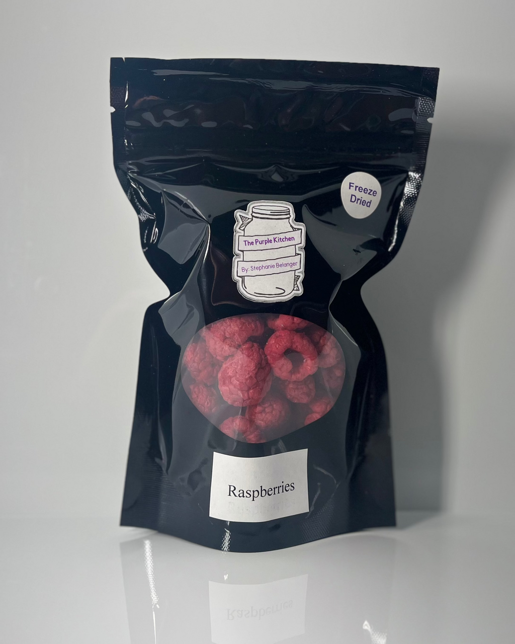 Black package of freeze dried raspberries on a white background