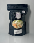 Black package with various freeze dried vegetables on a white surface