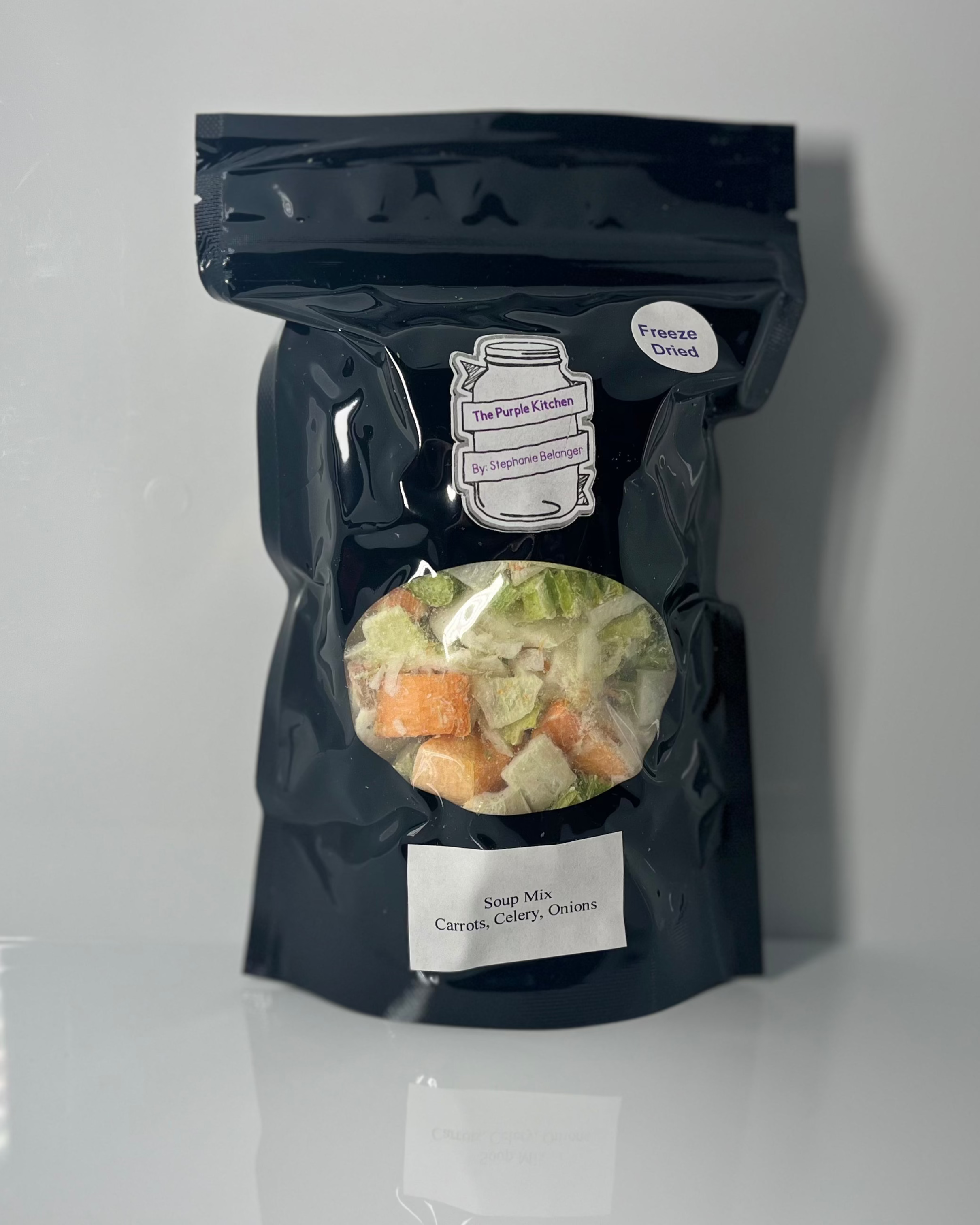 Black package with various freeze dried vegetables on a white surface