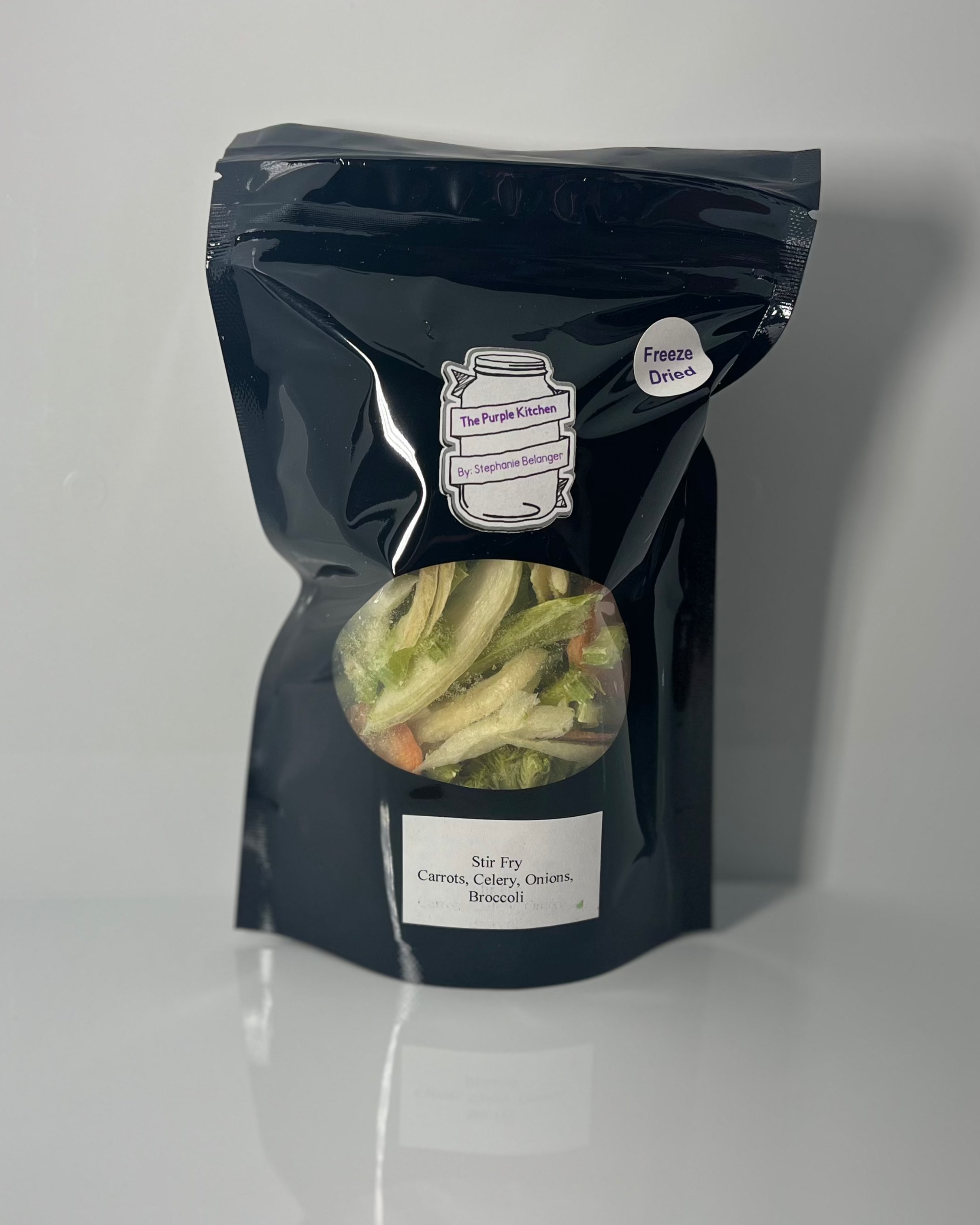 Black package with various freeze dried vegetables on a white. background